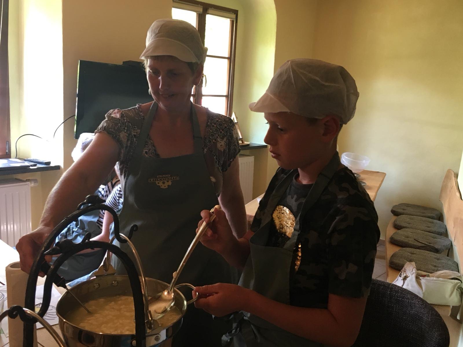 Petra zeigt am Kupferkessel, wie Käse entsteht